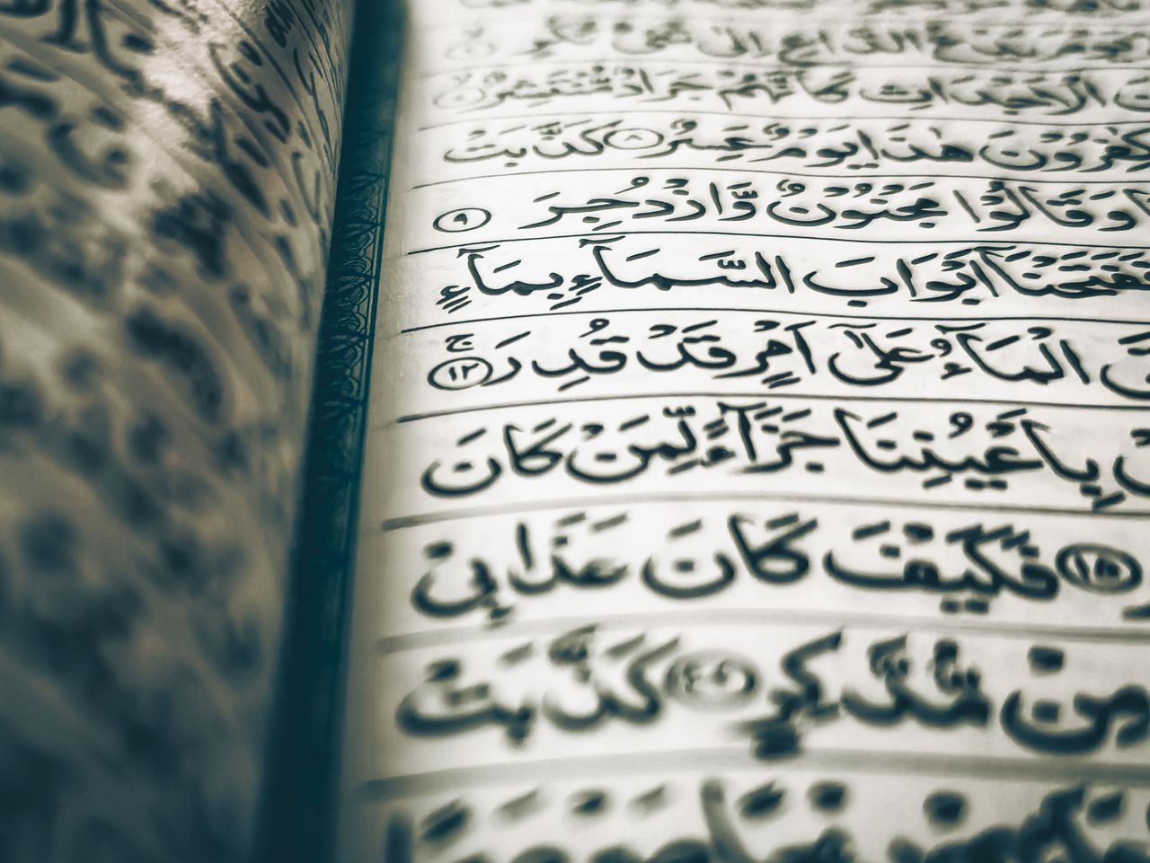 Detailed view of Arabic calligraphy in a religious text, highlighting intricate script and craftsmanship.