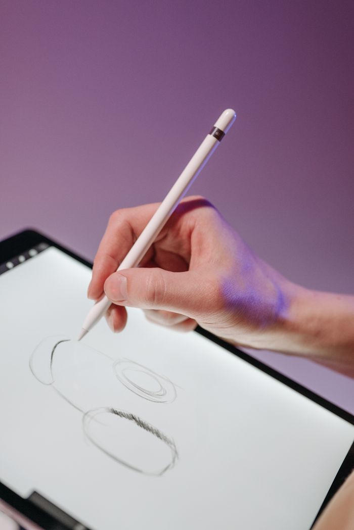 A hand uses a stylus to draw on a digital tablet, demonstrating modern digital art skills.